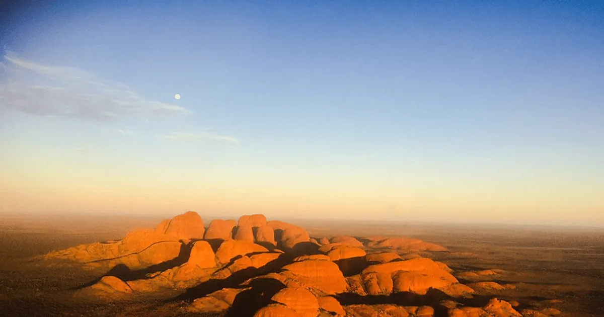 Die Kuppeln des Kata Tjuta bei Sonnenaufgang orange beleuchtet, aus der Luft über der Ebene gesehen