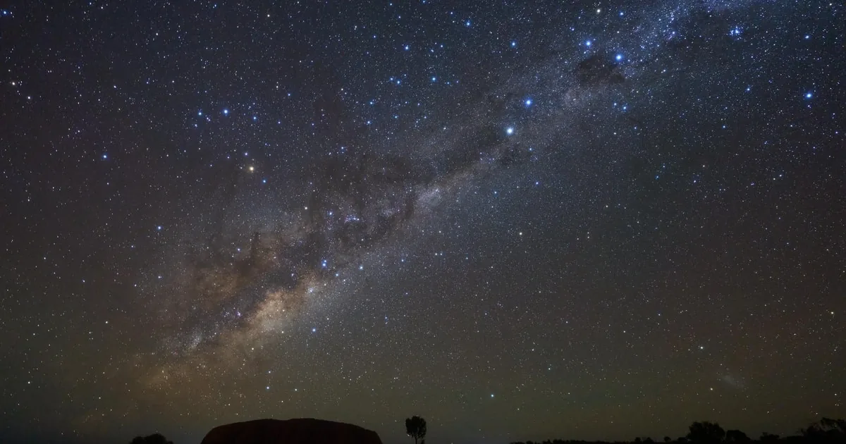 La Via Lattea sul parco buio, con un tenue profilo della roccia all'orizzonte