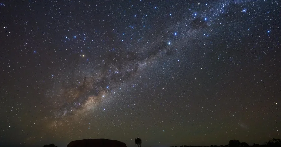 Die Milchstraße wölbt sich über den dunklen Nationalpark, am Horizont die Umrisse des Landes